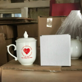 Cốc sứ in logo Nhà Khách Tỉnh Ủy Bình Định dáng bầu có nắp quai bán tim màu trắng XG-LS88