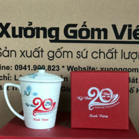 Cốc sứ in logo Kỷ Niệm 20 Năm Thành Lập Chợ Hòa Khánh dáng vát có nắp màu trắng họa tiết sen xanh XG-LS135