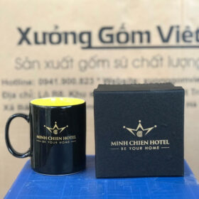 Ly sứ in logo Minh Chien Hotel dáng trụ cao có quai C màu đen lòng vàng XG-LS162