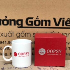 Ly sứ in logo OOPSY dáng trụ cao có quai C màu trắng XG-LS164