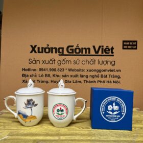 Cốc sứ Bát Tràng in logo Trung Tâm Giáo Dục Nghề Nghiệp-Giáo Dục Thường Xuyên huyện Phú Lộc - Tỉnh Thừa Thiên Huế dáng ngọn lửa có nắp màu trắng họa tiết hoa sen xanh kẻ chỉ vàng XG-LS199